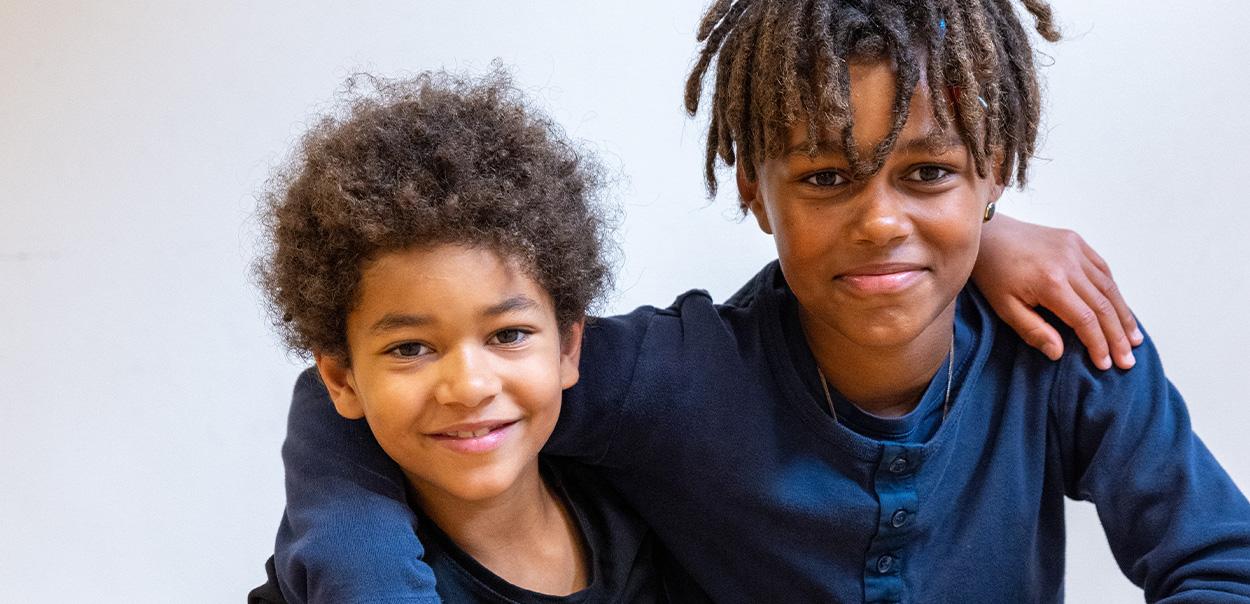 To glade børn som står arm i arm