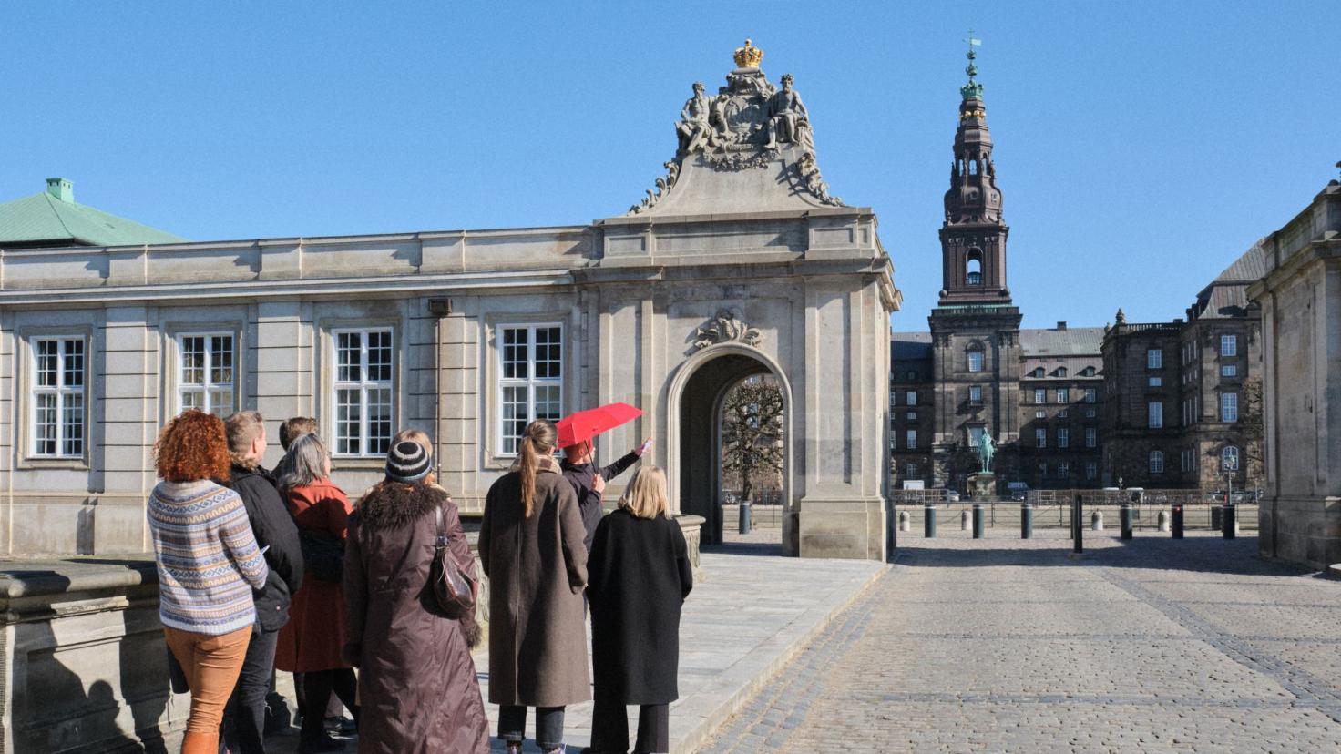 Gruppe af mennesker, der bliver vist rundt ved Marmorbroen af guide med rød paraply