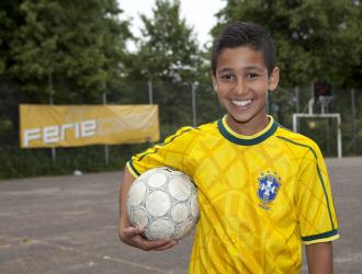 Dreng står med fodbold under armen