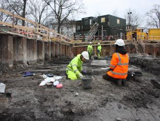 Arkæologer i udgravningsfelt i færd med at undersøge jorden