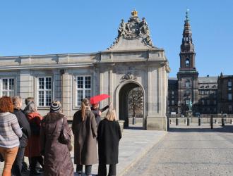 Gruppe af mennesker, der bliver vist rundt ved Marmorbroen af guide med rød paraply